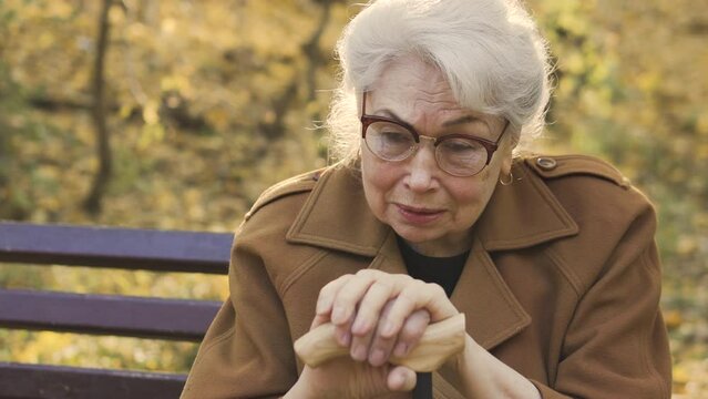 Old gray-haired lady suffering from her old age and worthlessness, worrying that she is no longer capable of anything and is no longer needed by anyone