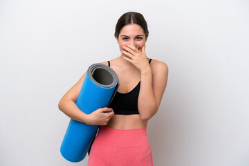 Young sport girl going to yoga classes while holding a mat isolated on white background happy and smiling covering mouth with hand