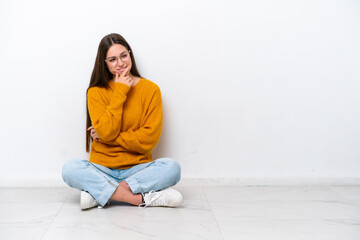 Young girl sitting on the floor isolated on white background looking to the side