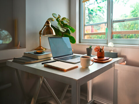Modern workplace with laptop, coffee cup, books and other items on table
