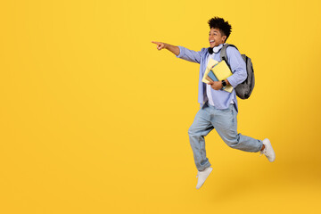 Joyful student jumping and pointing excitedly