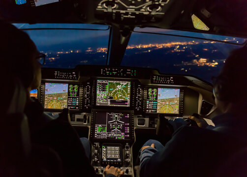 View from the cockpit of a modern airplane landing at an illuminated vilage at night