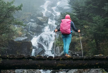 Photo sur Plexiglas Makalu Young woman with backpack and trekking poles enjoying power mountain river waterfall on wooden bridge during Makalu Barun National Park trek in Nepal. Mountain hiking and active people concept image