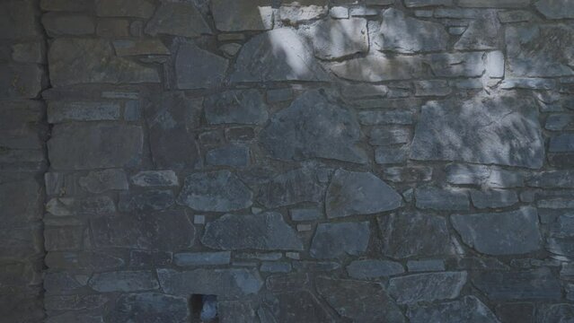 Stone wall texture on sunny country house background. White stone wall of country house on tropical island in shadow in sunlit morning