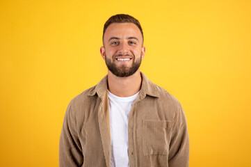 Smiling handsome millennial european guy with beard in casual look at camera