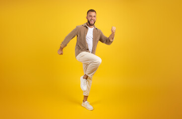 Cheerful young caucasian guy with beard in casual has fun, dance, jumping, freezes in air