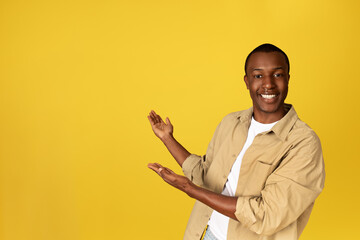 Positive young african american man student in casual point hands at copy space