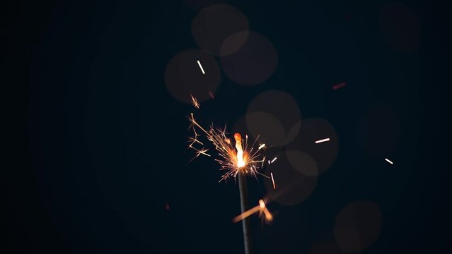 Burning sparkler on black background with lens flare lights. New year party background. New year sparkles.