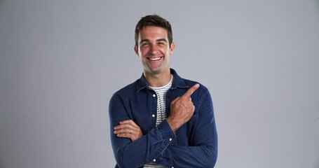Man, pointing and advertising in studio mockup, smile on face and discount promotion by gray background. Person, happy portrait with finger emoji, sales offer and bonus with marketing presentation - Powered by Adobe
