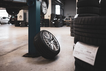 a complete wheel leans against a pillar in a car repair shop