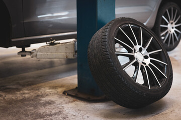 a complete wheel leans against a pillar in a car repair shop