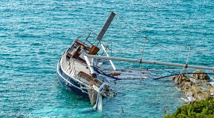 Rocky coast with stranded damaged sailboat with broken mast in French Mediterranean sea after storm...