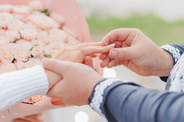 Wearing a ring at the engagement ceremony. Man putting engagement ring on woman's finger, closeup....