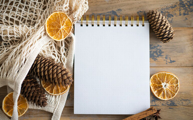 Notepad with copy space on the wooden background and natural Christmas decoration. Mockup. Eco friendly concept