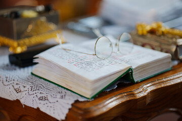 Glasses on the pages of an open Bible on a table in a church. 