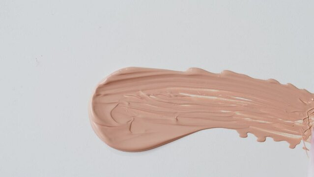 Beauty shop, Foundation face make-up close up smudge, smear. Cosmetic liquid foundation cream beige color smudge smearing. 