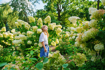 Cute teenage girl in flowering hydrangea bushes.
