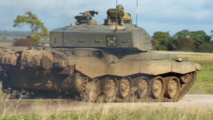 Commander and gunner directing a British army FV4034 Challenger 2 ii main battle tank moving along a dirt track at speed, on a military exercise, Wiltshire UK