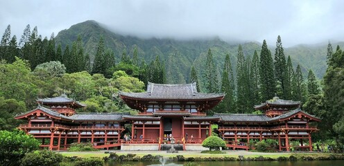 Panoramic landscape of the historic Byodo-In Temple on the background of a foggy forested hill