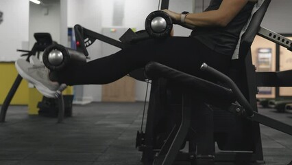 Young woman doing leg extension exercise on a seated machine.