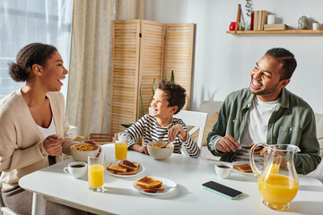 beautiful modern african american family talking and smiling while having delicious breakfast