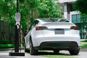 EV electric car charging in green sustainable city outdoor garden in summer. Urban sustainability...