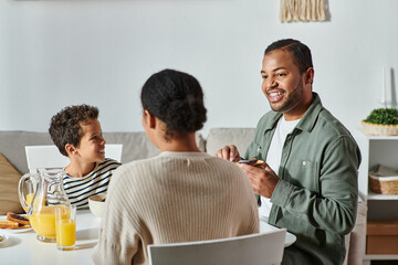 back view of african american woman enjoying delicious breakfast with her jolly son and husband