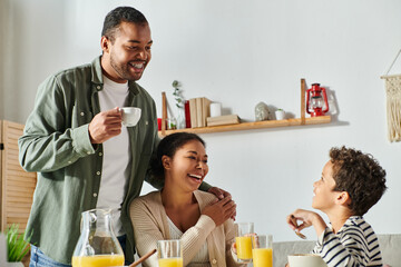 cheerful african american family in casual home wear having delicious breakfast, hand on shoulder