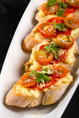 Starter or antipasto - Bruschetta with slices of Spanish sausage on French bread with cherry tomatoes and mozzarella cheese