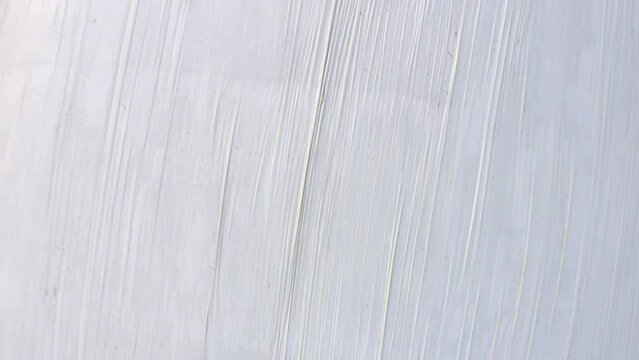 Drone launch over a white silo bale in a green meadow
