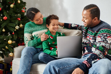 jolly african american family having great time while watching movie on laptop on Christmas morning