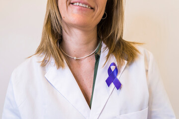 Close-up of purple ribbon pinned on white lab coat of female doctor.
