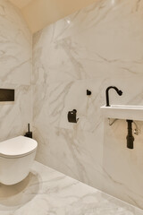 a bathroom with marble walls and white fixtures on the wall, there is a toilet in the corner next...