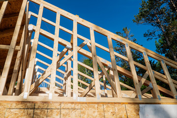 Wood rafters at a new home construction building site on a sunny day with blue sky.