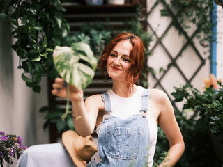 A woman gardening plants on a balcony, nurturing green life in an urban environment