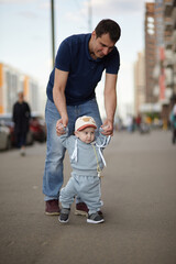 the first steps of the child are held by the father's hands.