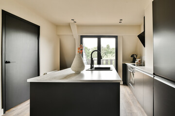 Fototapeta na wymiar a modern kitchen with black cabinets and white counter tops in the center of the room is an open door that leads to a balcony