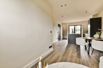 a living room with wood flooring and white walls in the center of the room is a small dining table