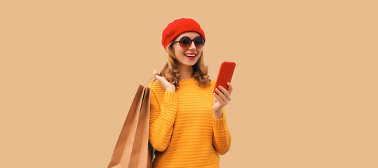 Autumn style outfit, portrait of stylish smiling young woman model with mobile phone holds shopping...
