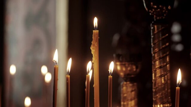Burning candles in the Orthodox church. Wax candles burn in the dark in church against dark. Church candles burn on a large gold candlestick in the church. 