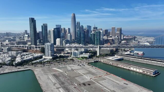 San Francisco, USA,  flight toward the Skyscraper Skyline of "South of Market" (SoMA) district and famous Salesforce Tower during sunny day, while overflying harbor - aerial video footage 