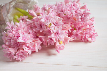 Bouquet of pink hyacinth flowers on a white wooden background, spring card.