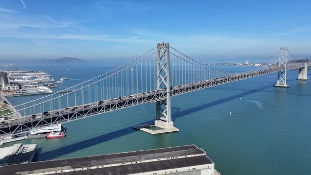 flight along San Francisco–Oakland Bay Bridge,  a double-decked suspension spans - across San Francisco Bay - Car and Truck traffic driving on both decks on Interstate 80 - aerial video footage