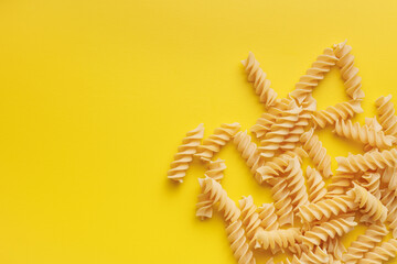 Uncooked fusilli pasta. Uncooked italian pasta on yellow background.