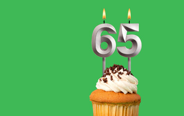 Birthday with number 65 candle and cupcake - Anniversary card on green color background
