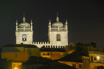 Fototapeta na wymiar Se do Porto the white Cathedral of the city Porto at illuminated night over the houses of the town, Porto, Portugal