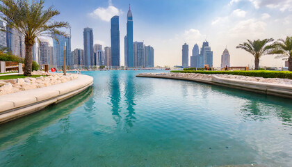 water pond near the entrance to dubai mall and on promenade embankment with skyscrapers in the background - obrazy, fototapety, plakaty