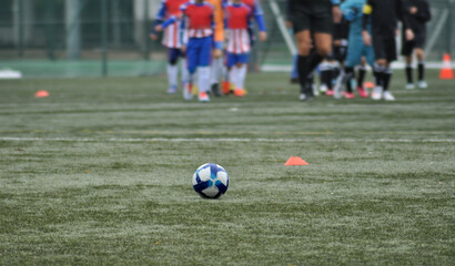 Soccer ball in the middle of the lawn with teams of children's players entering the field,...