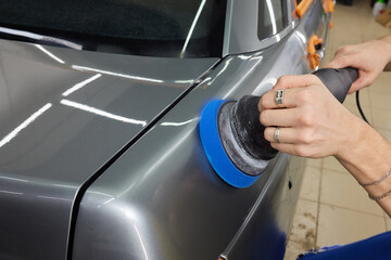 Car detailing - Hands with orbital polisher in auto repair shop