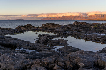 Obraz premium View of famara cliffs at sunset with ocean pools in the foreground, lanzarote